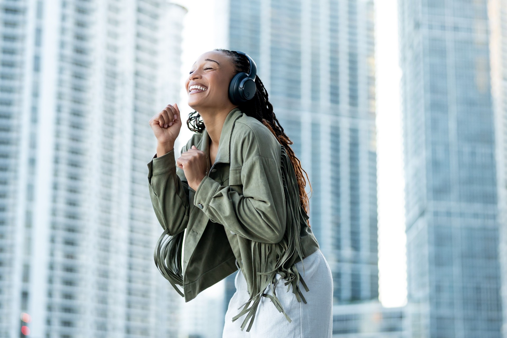 Portrait of a beautiful and happy African American woman, listening to her music on her headphones, dancing and having fun by the river in Miami Riverwalk, Downtown, FL